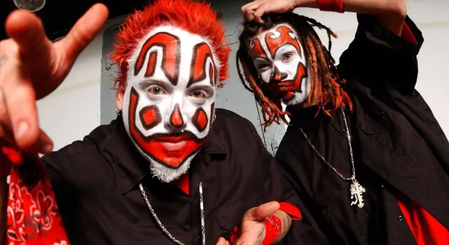 Deux membres du groupe Insane Clown Posse, visage peint en clown, cheveux rouges et dreadlocks, portent des chemises noires et des bandanas rouges.