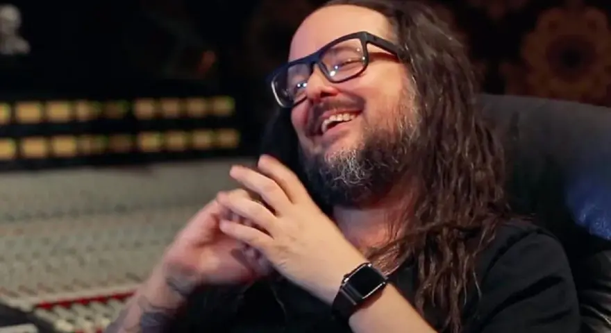 Jonathan Davis, le chanteur de Korn, rit en studio d'enregistrement, lunettes sur le nez et longue chevelure brune.
