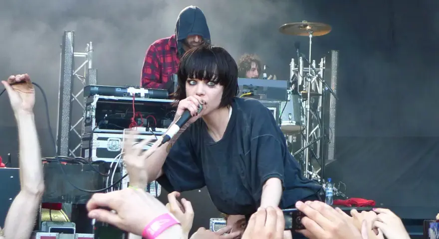 La chanteuse de Crystal Castles, Alice Glass, chante devant une foule. Un autre membre est derrière elle.