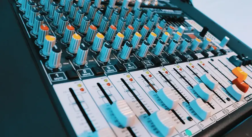 Console de mixage audio avec de nombreux boutons et curseurs. Les niveaux de volume peuvent être ajustés pour un son parfait, peut-être jusqu'à 40 décibels.