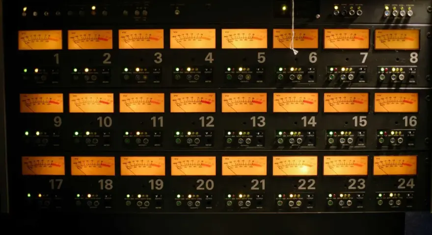 Rack d'équipements audio avec 24 vu-mètres orange illuminés, indiquant des niveaux sonores pouvant atteindre 76 décibels équivalents.