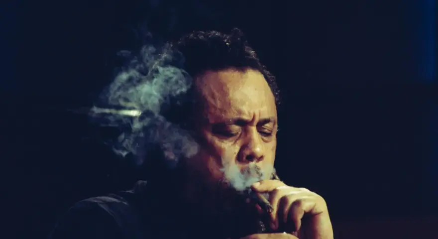 Charlie Mingus, le légendaire contrebassiste, exhale une fumée épaisse, les yeux clos, absorbé par sa musique.
