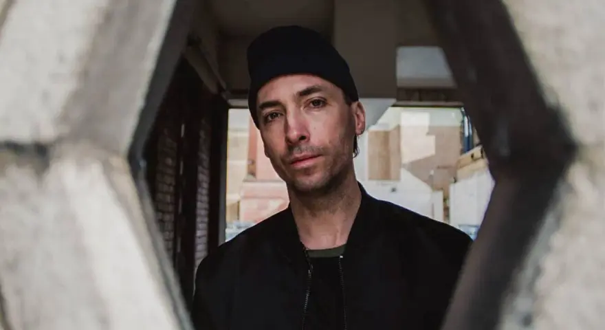 Tim Hecker, artiste sonore, regarde à travers une structure architecturale.