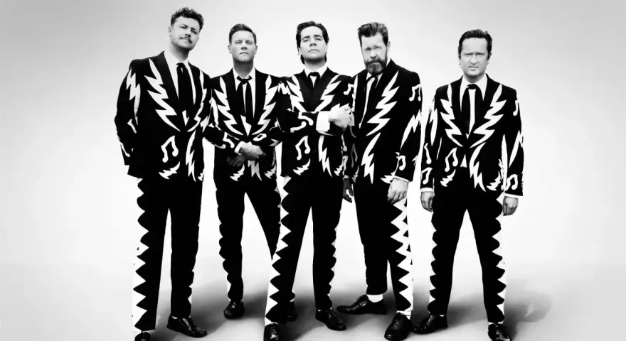 Les membres de The Hives posent en costumes noirs et blancs à motifs d'éclairs et de notes de musique.