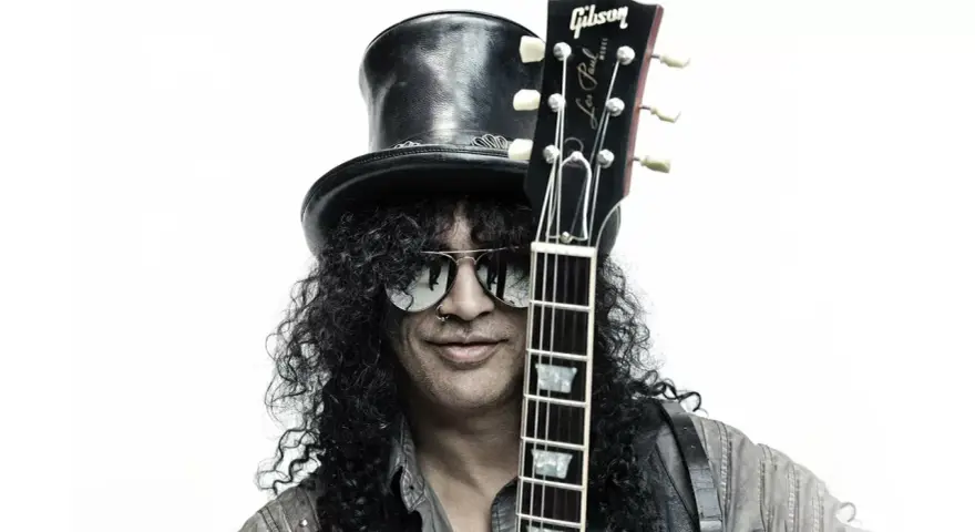 Le guitariste Slash, avec son chapeau haut-de-forme et ses lunettes de soleil, pose avec sa guitare Gibson Les Paul.