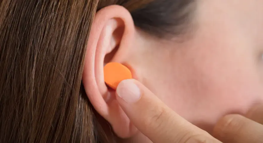 Une personne insère une boule quies en mousse orange dans son oreille. Peut on laver des boules quies en mousse ?