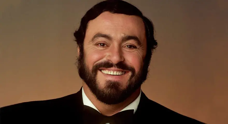 Portrait souriant de Luciano Pavarotti, le célèbre chanteur rock italien, en costume noir et nœud papillon.