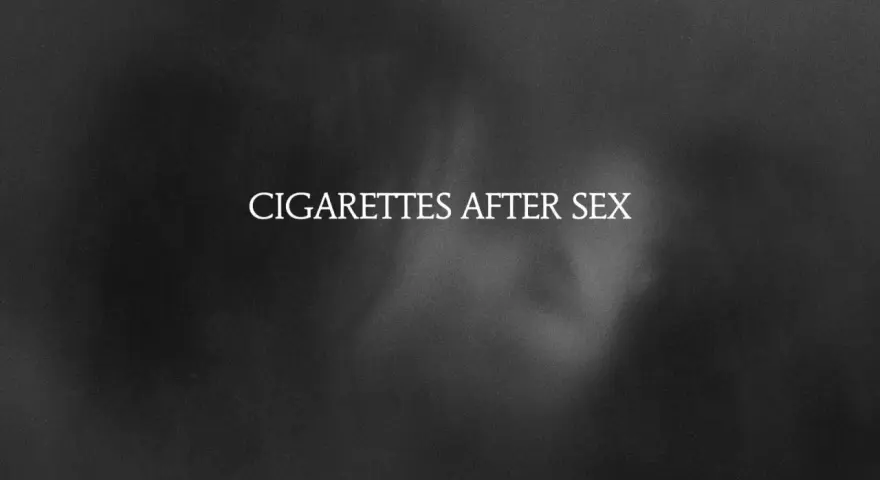 Texte blanc "CIGARETTES AFTER SEX" sur fond sombre et flou, évoquant une ambiance intime et mélancolique.