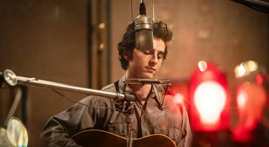 Un jeune homme à la guitare et à l'harmonica, dans un style de musique rappelant Bob Dylan, enregistre en studio.