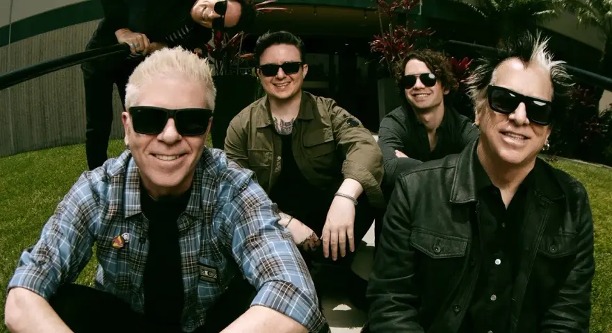 Les membres de The Offspring posent ensemble, souriants et portant des lunettes de soleil. Le groupe semble prêt pour une nouvelle aventure musicale.