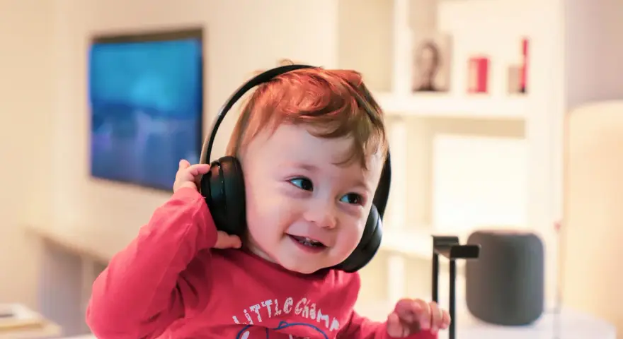 Un enfant qui ne supporte pas le bruit trouve le calme avec ses écouteurs, un sourire aux lèvres.