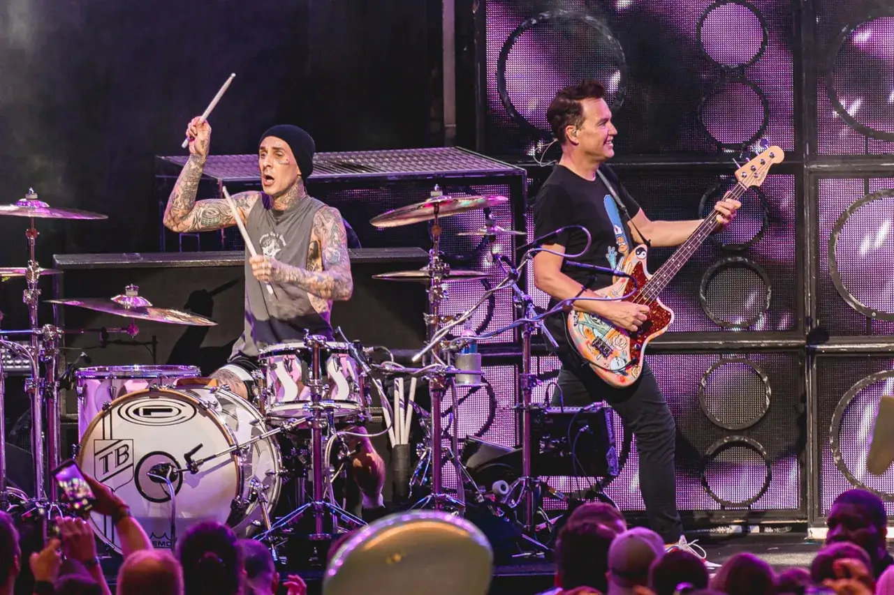 Travis Barker frappe la batterie et Mark Hoppus joue de la basse, deux membres de blink-182 en pleine performance sur scène.