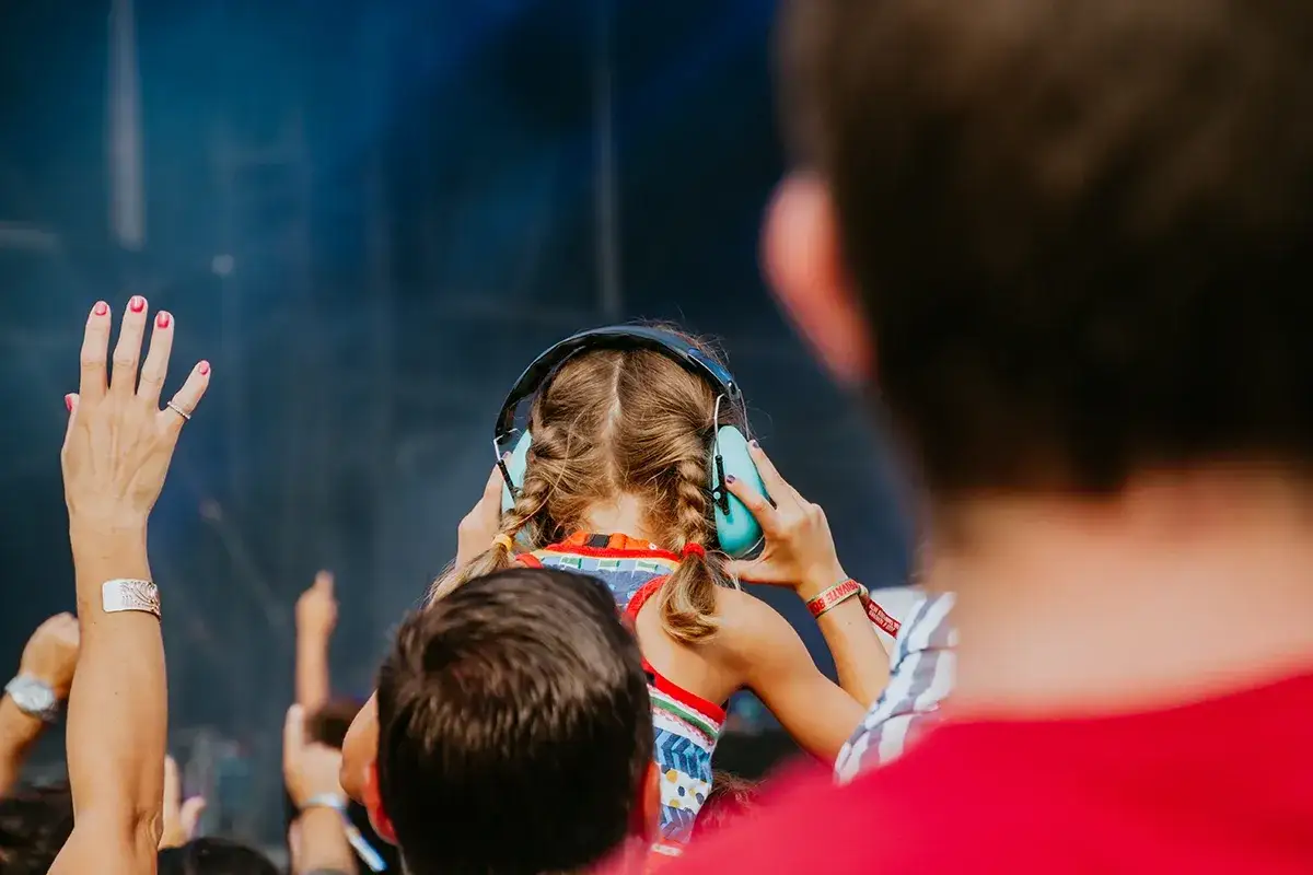 Une jeune fille aux tresses bleues porte un casque anti-bruit pour se protéger des 95 db équivalent d'un concert.