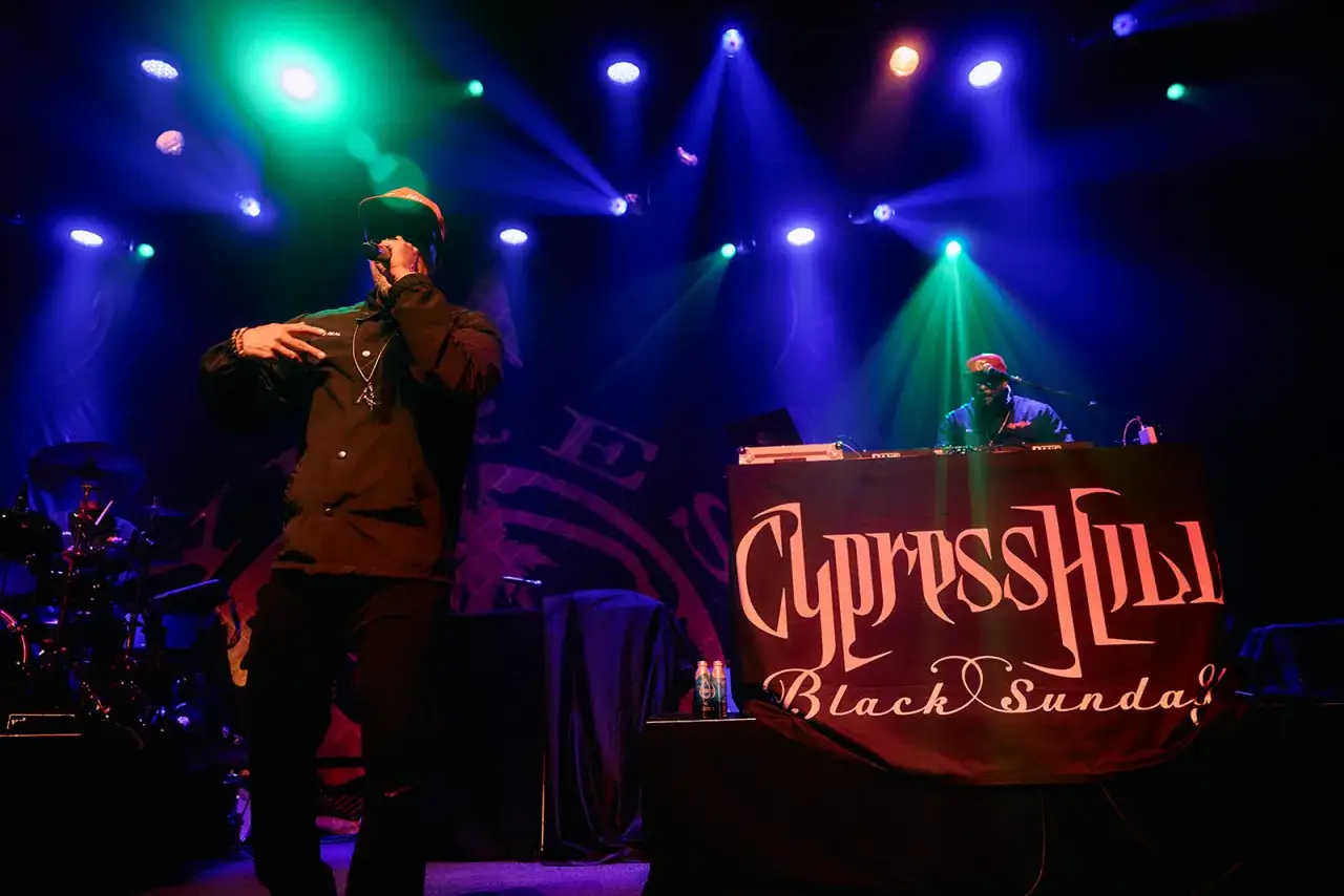 Sur sc&egrave;ne, des membres de Cypress Hill enflamment le public sous des jeux de lumi&egrave;re bleus et verts.