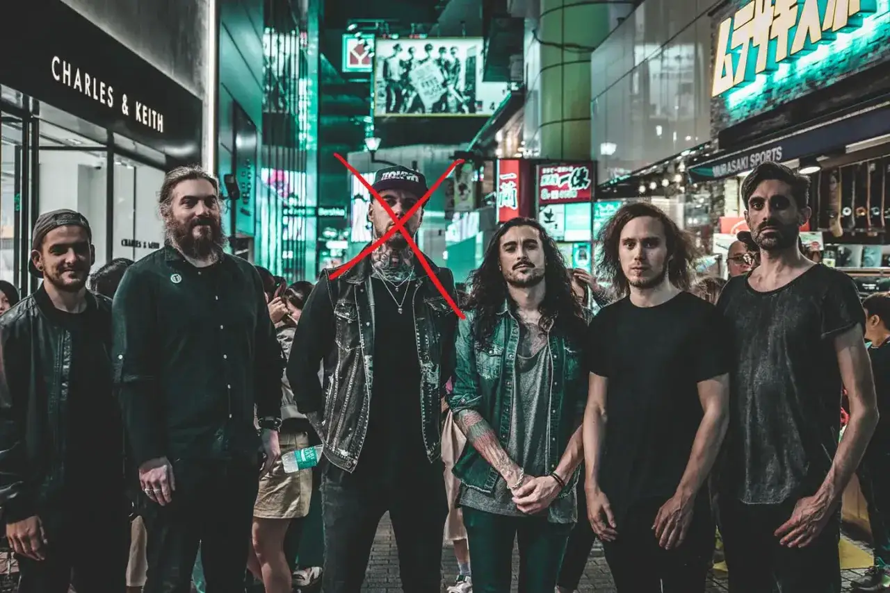 Six hommes posent dans une rue animée de Tokyo, un X rouge sur l'un d'eux, trahissant les martyrs.