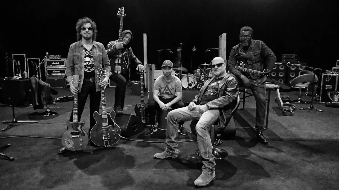 Le groupe Trust pose avec leurs guitares, pr&ecirc;ts &agrave; faire vibrer la sc&egrave;ne.