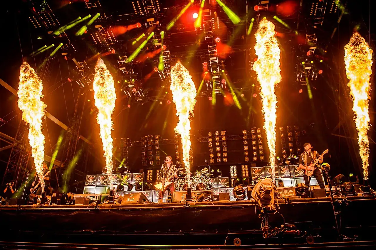 Sur scène, des guitaristes jouent sous des jets de flammes spectaculaires, l'énergie est running wild.