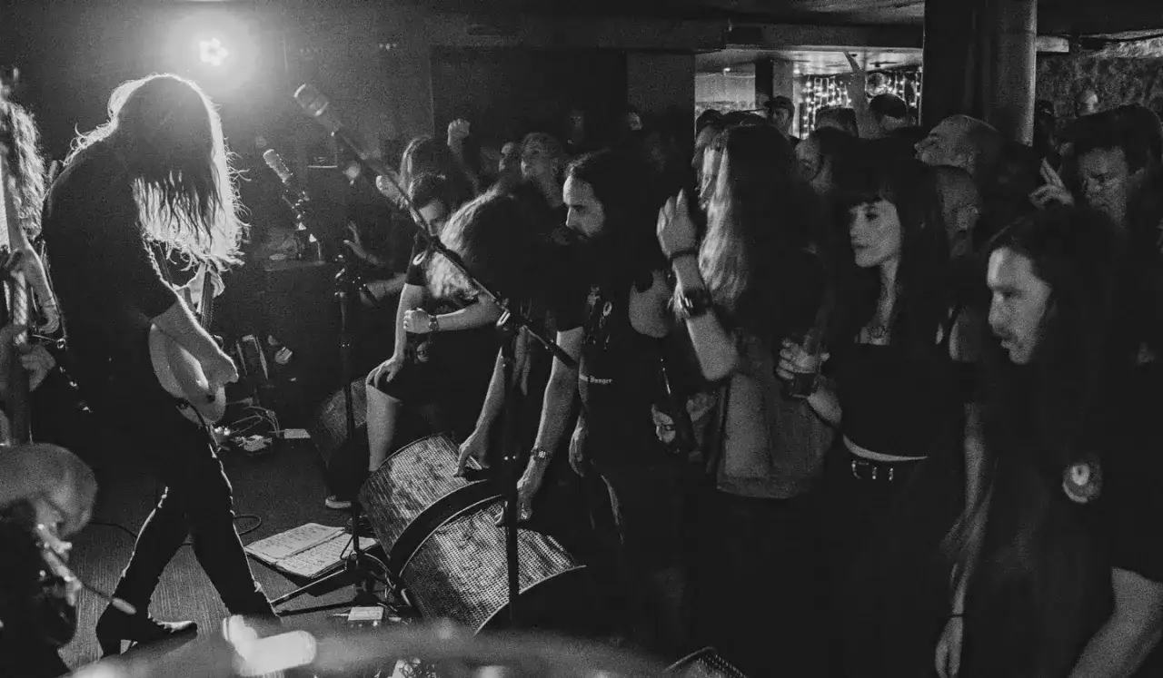 Sc&egrave;ne live intense d'Uncle Acid and the Deadbeats, le guitariste au premier plan, foule en d&eacute;lire.