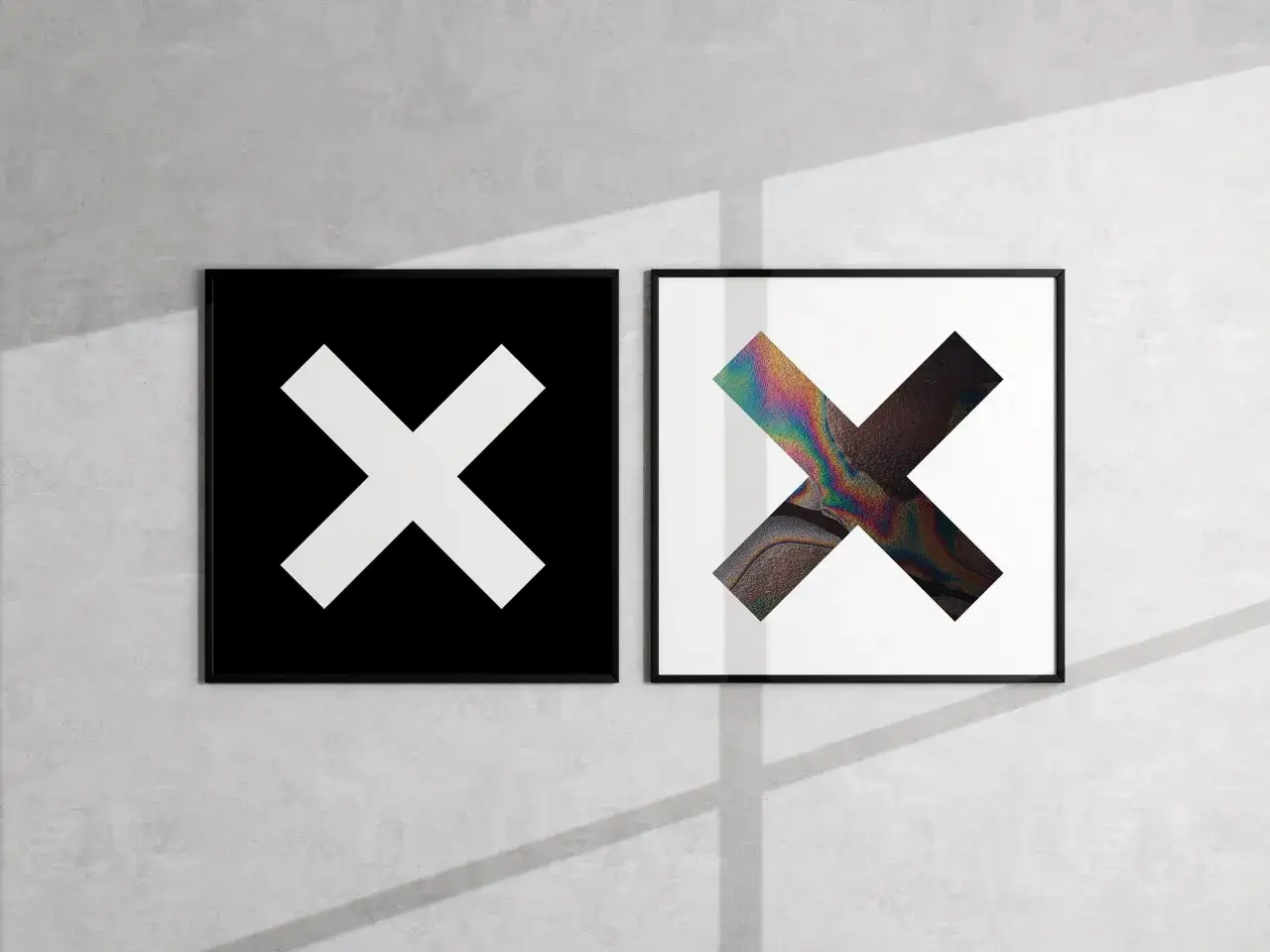 Deux cadres sur un mur de béton : l'un avec un X blanc sur fond noir, l'autre avec un X aux couleurs irisées. Une ambiance minimaliste rappelant les albums de The xx.
