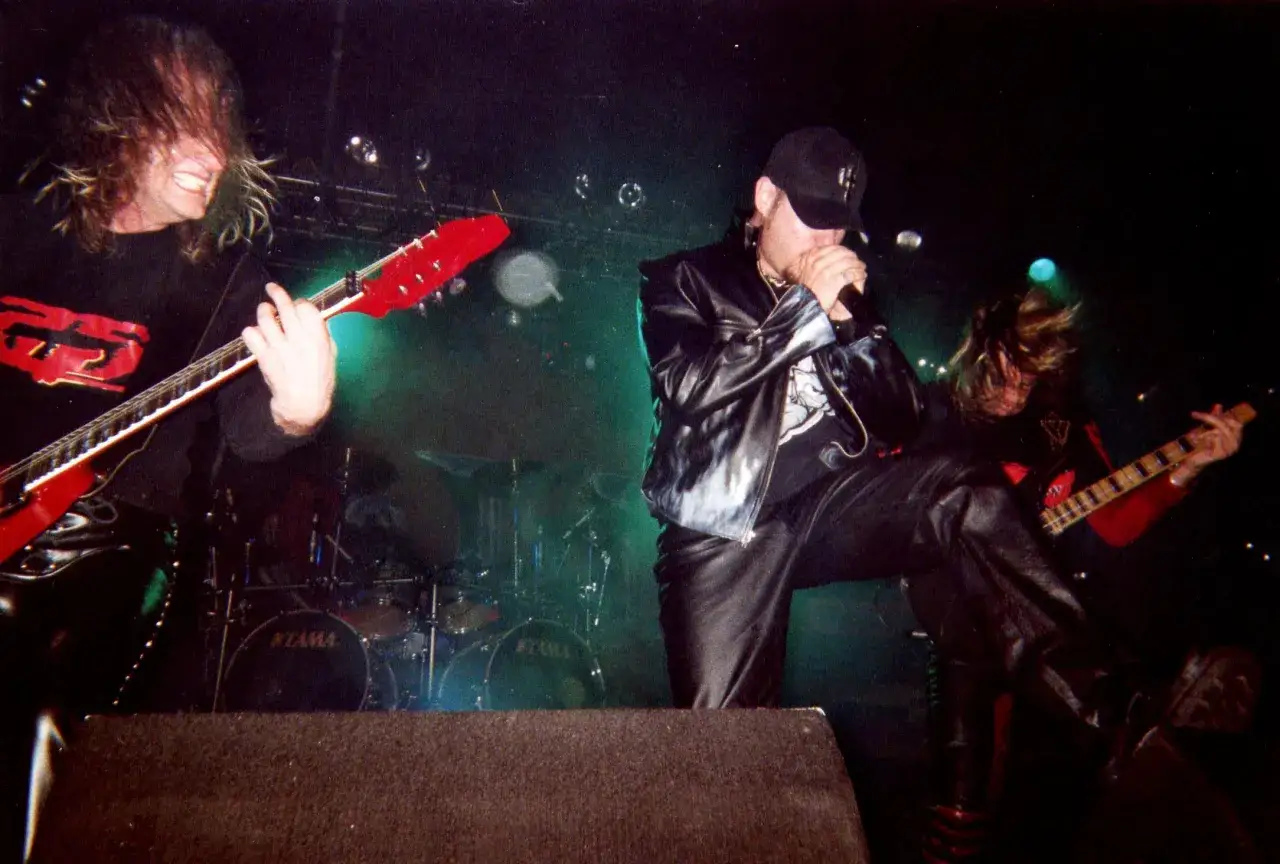 Les membres de Judas Priest en pleine action sur scène, guitares électriques et micro en main, dans une ambiance électrique.