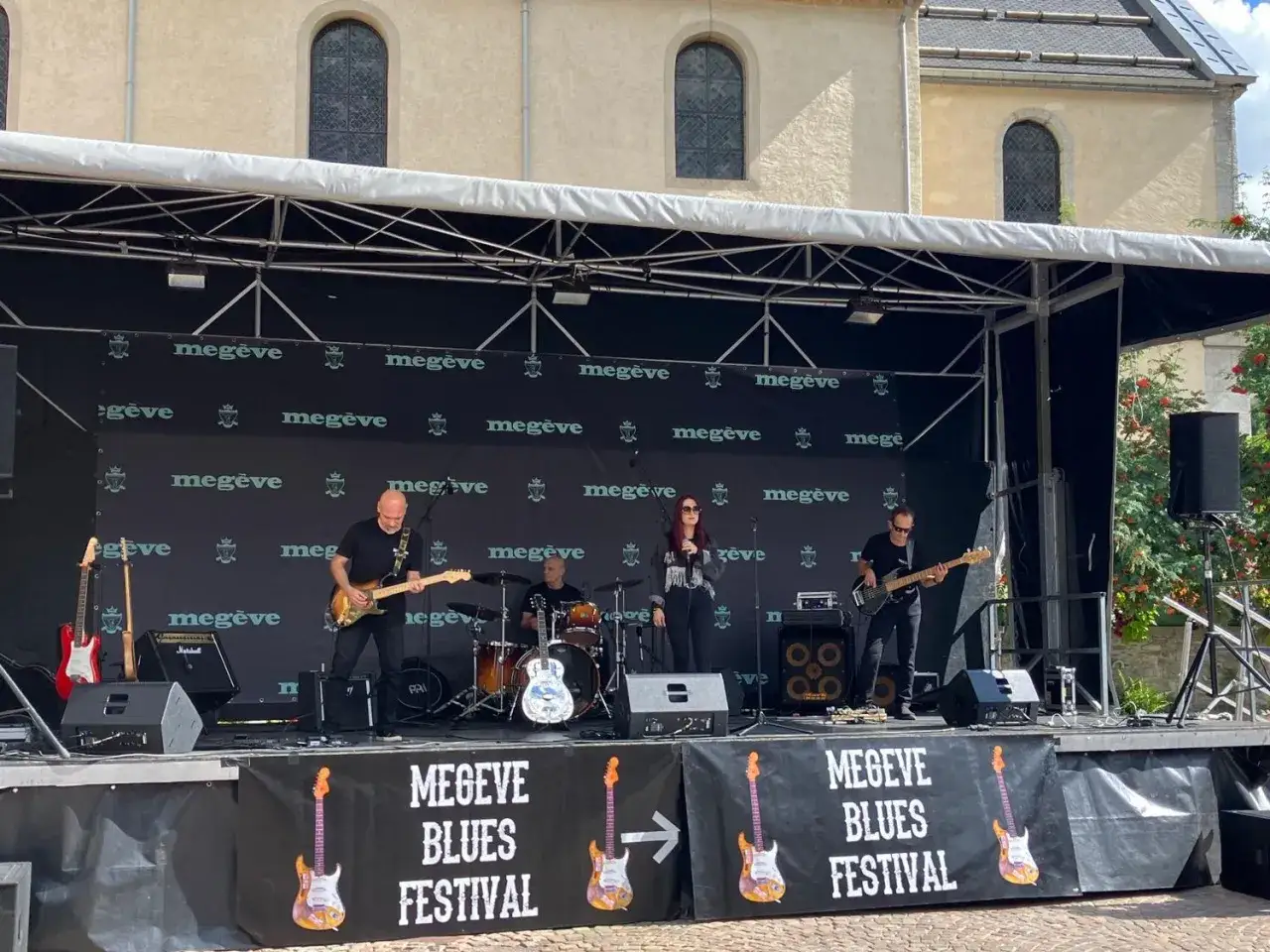 Un groupe de musique joue sur scène lors du festival de blues de Megève. Le chanteur blues français est au centre, guitare à la main.