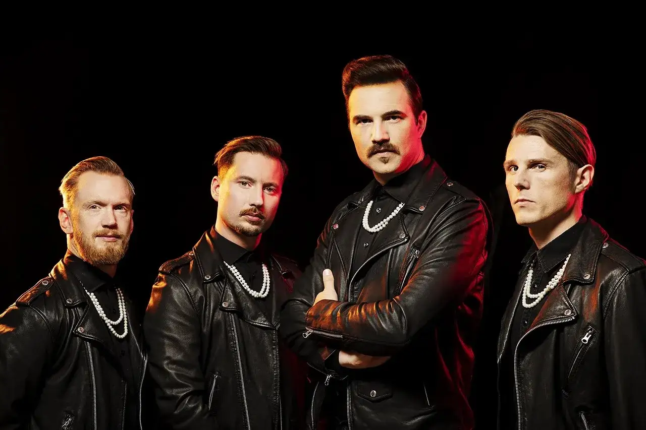 Quatre hommes en blousons de cuir noir et colliers de perles, un style qui évoque une royal republic moderne.