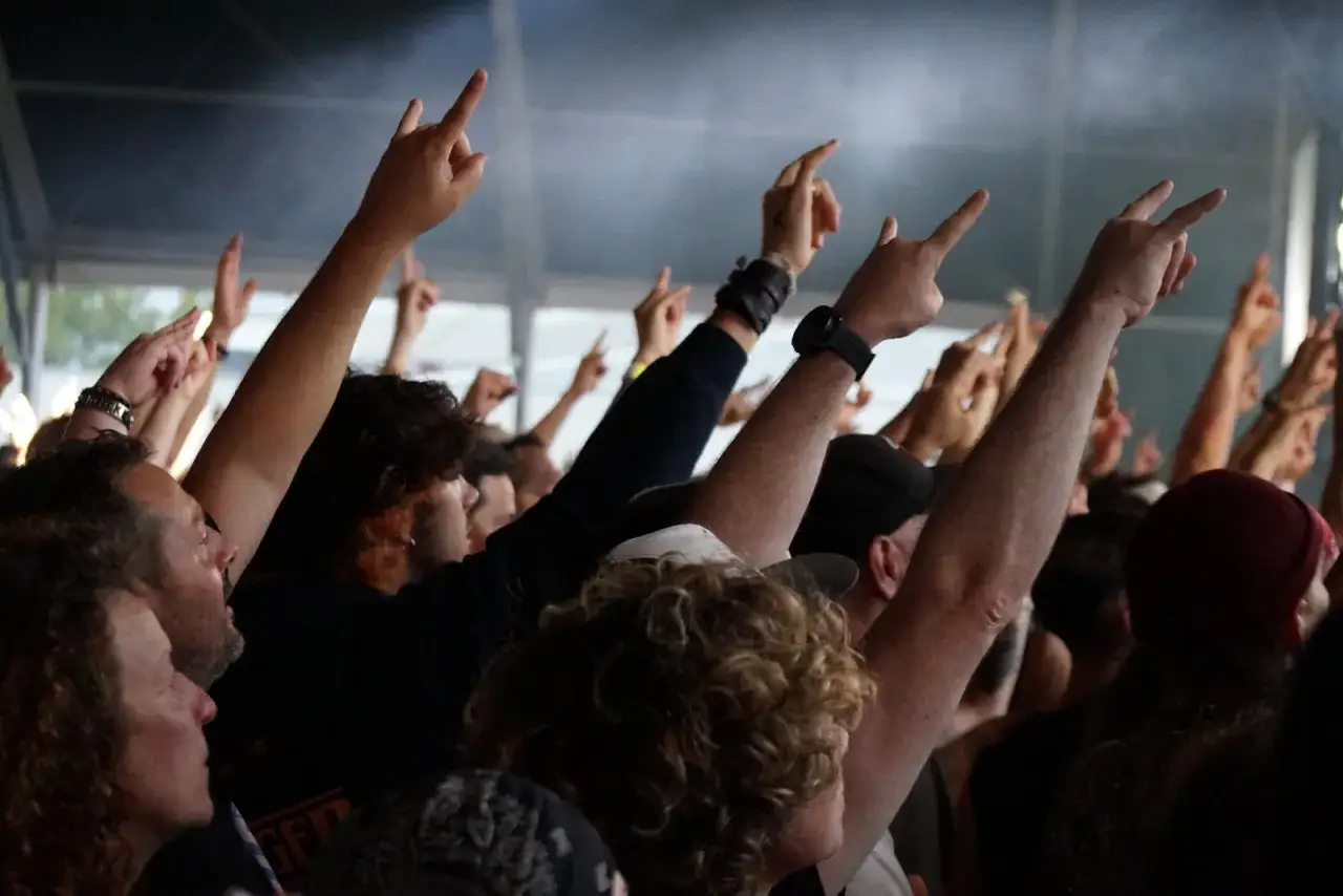 Foule en délire, mains levées en signe de rock, lors d'un concert d'un groupe metal connu.