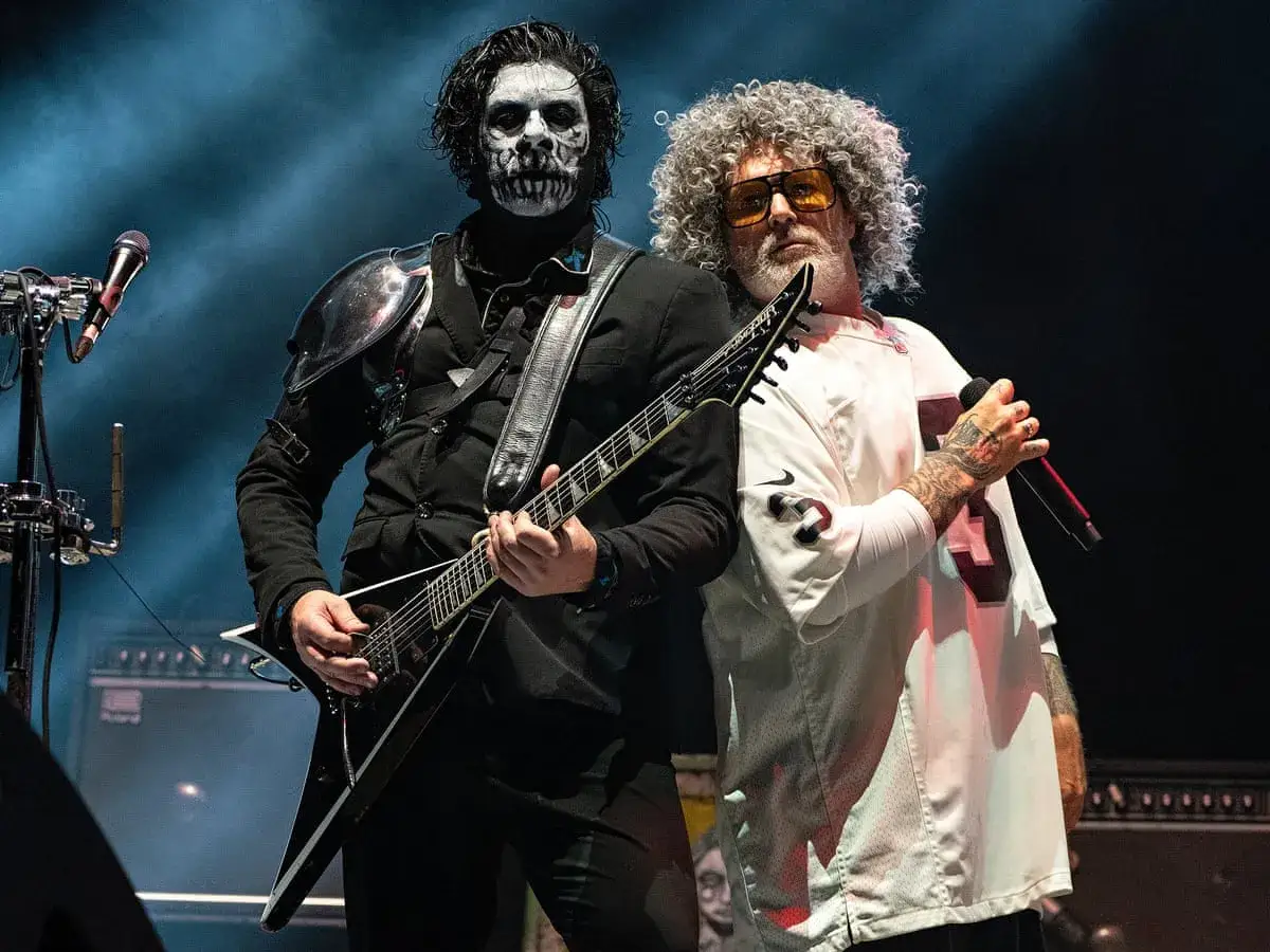 Deux membres de Limp Bizkit sur scène : un guitariste au maquillage de squelette et un chanteur à la chevelure afro et portant un maillot de sport.