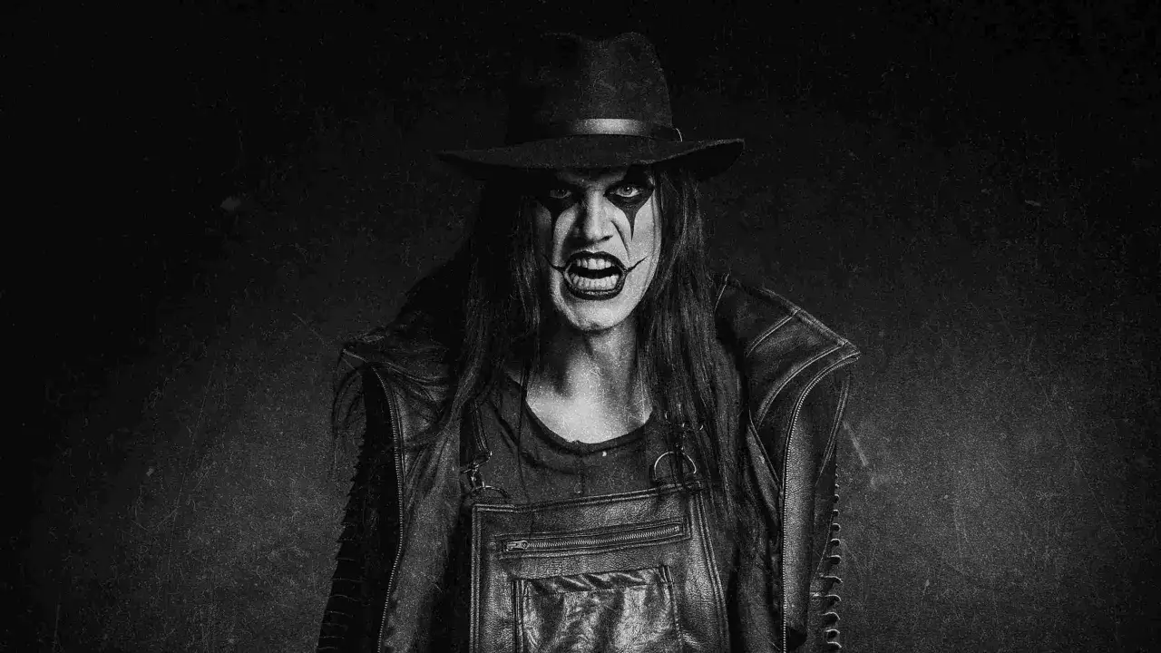 Un chanteur avatar au maquillage de clown effrayant, portant un chapeau et des bretelles en cuir, rugit dans un style sombre et dramatique.