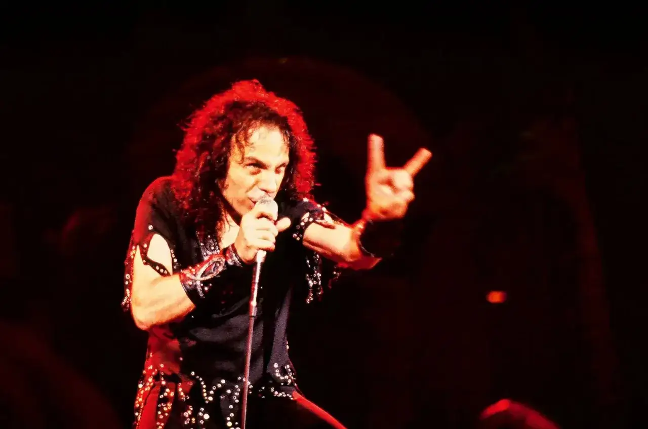 Ronnie James Dio, icône du heavy metal, chante sur scène, son geste de la main évoquant le heaven and hell de la musique.