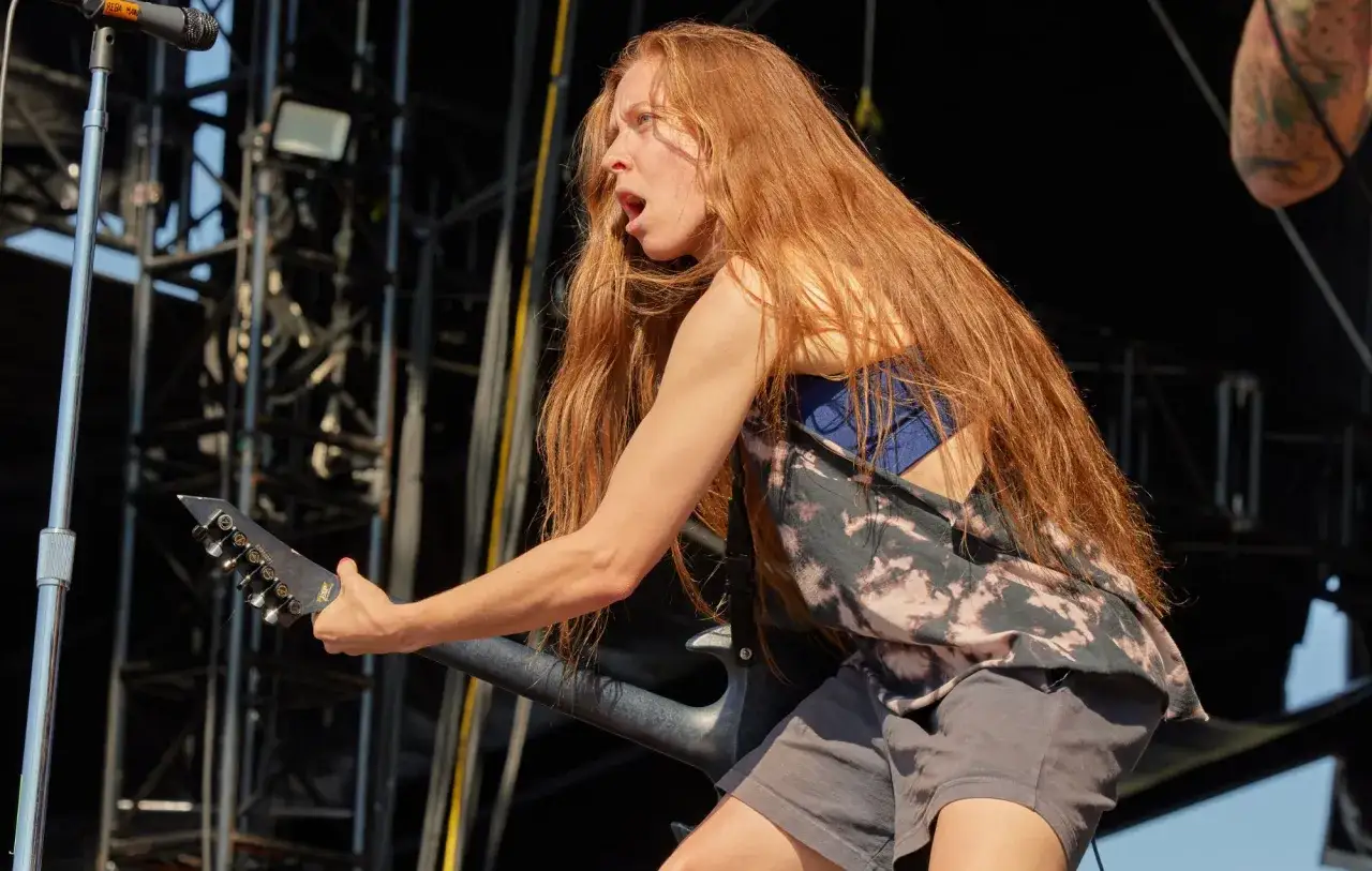 Reba Meyers, guitariste aux longs cheveux roux, d&eacute;cha&icirc;ne un riff sur sc&egrave;ne, le visage tendu par l'effort et la passion.
