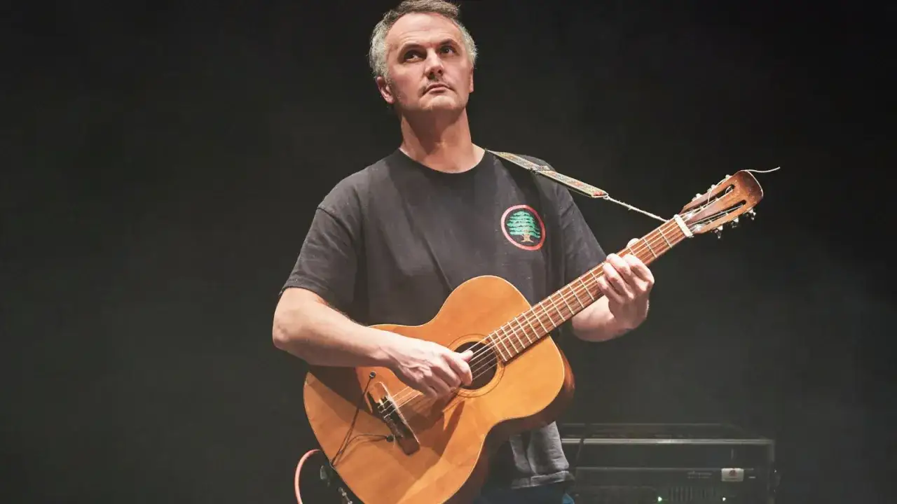 Un homme joue de la guitare sur sc&egrave;ne, son regard perdu dans le lointain, comme s'il contemplait le mount eerie.
