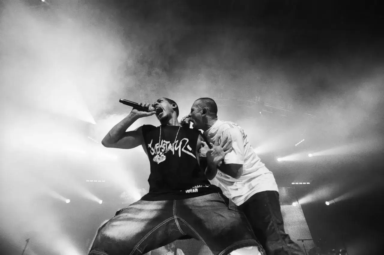 Deux rappeurs sur scène, l'un tenant un micro, incarnent la diversité des différents styles de rap français.