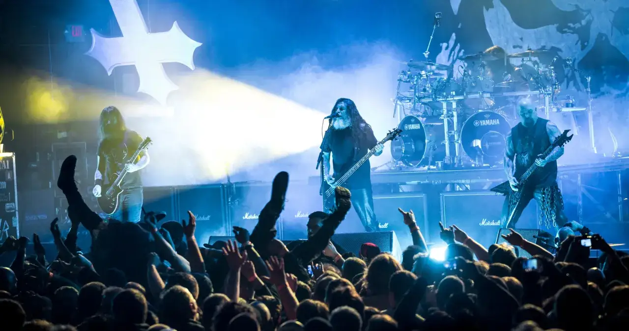 Les membres de Slayer enflamment la sc&egrave;ne devant une foule en d&eacute;lire. Lumi&egrave;res bleues et jaunes, guitares &eacute;lectriques, batterie Yamaha et amplis Marshall cr&eacute;ent une ambiance survolt&eacute;e.