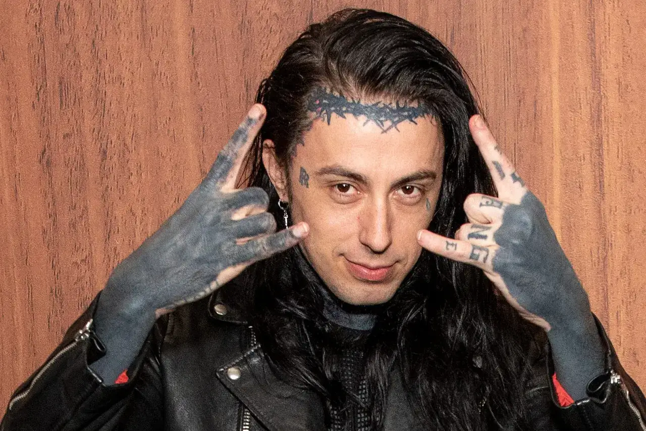 Le chanteur Falling in Reverse, Ronnie Radke, fait le signe des cornes avec ses mains tatou&eacute;es, une couronne d'&eacute;pines tatou&eacute;e sur le front.