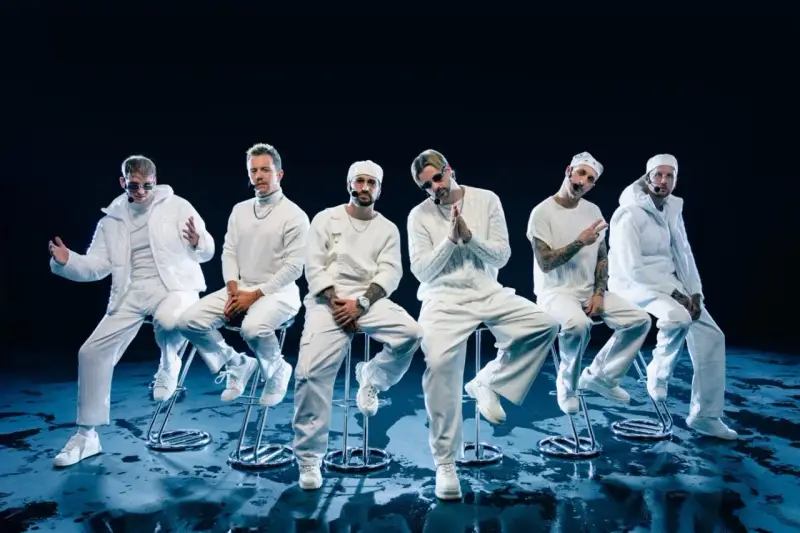 Six hommes en tenue blanche, assis sur des tabourets, évoquant l'univers des albums de Electric Callboy.