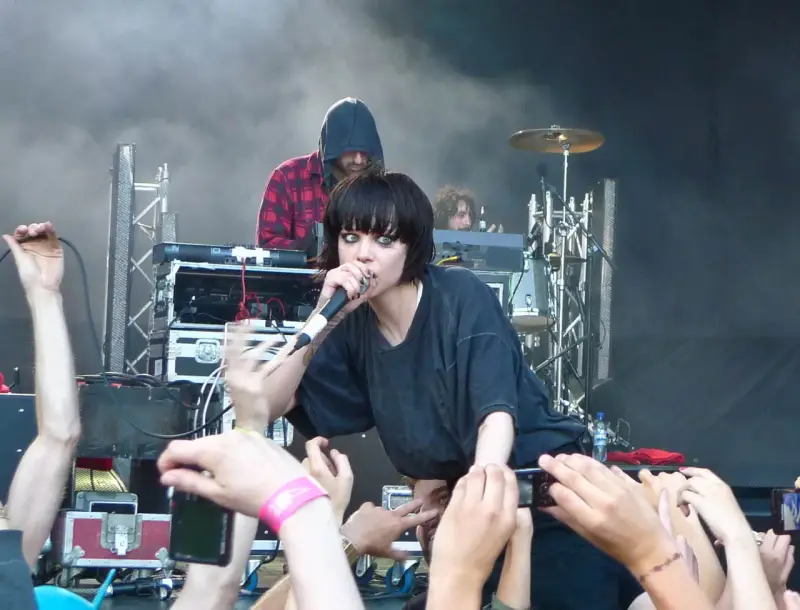La chanteuse de Crystal Castles, Alice Glass, chante devant une foule. Un autre membre est derrière elle.